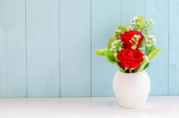 白と青の木の背景に白い花瓶に白いデイジーの花と緑の葉を持つ赤いバラ — ストック写真