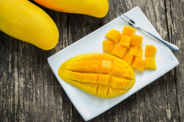 Tahta masadaki beyaz tabakta altın mango dilimi, tropik meyve, mango meyvesi, yaz meyvesi.