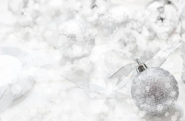 Silver Christmas ball with ribbon on white spakles bokeh light background, Christmas background