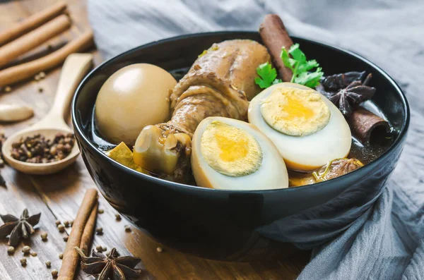 鸡蛋和鸡肉炖菜 配上调料和褐色酱汁 放在木桌上的黑碗里 亚洲菜 中国菜 泰国菜 — 图库照片