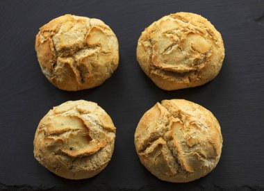 Dört somun ev yapımı ekmek, koyu bir levhada, Üst Manzara