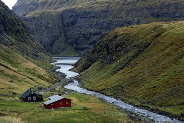Saksun 'un uzak yamaçlarındaki muhteşem köyde inanılmaz bir göl. Küçük renkli evler, fiyortlar ve deniz kıyısında. Streymoy, Faroe Adaları. Avrupa