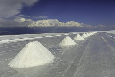 Küçük tuzlu tepeler grubu ve Salt Lake Salar de Uyuni 'deki yansımaları. Andes Altiplano, Bolivya, Güney Amerika. Ön plandaki tepelere odaklan
