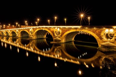 Köprü Pont Neuf gece aydınlandı. Aydınlanmanın küçük bir parçası kırıldı. Garonne nehrinin güzel yansıması. Toulouse, Fransa