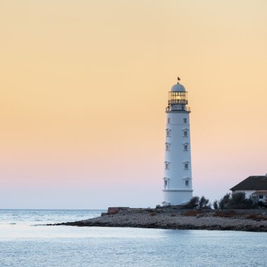 Lighthouse searchlight beam near ocean at sunset clipart
