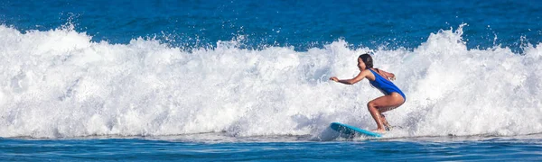 Surfeskolen. Vakker ung kvinne i badedrakt havner i havet. – stockfoto