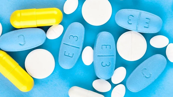 Verschiedene pharmazeutische Medizin-Pillen, Tabletten und Kapseln auf blauem Hintergrund — Stockfoto