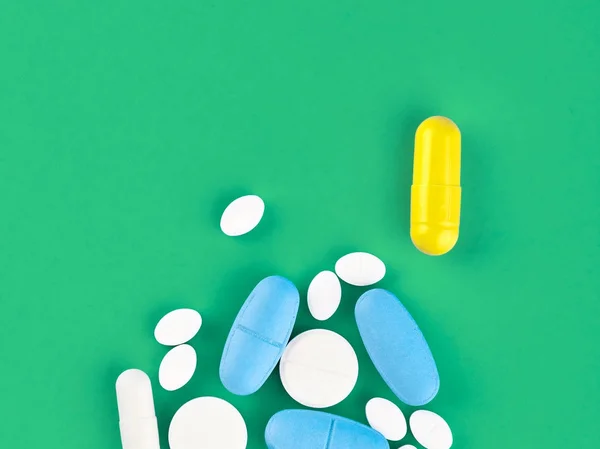 Assorted pharmaceutical medicine pills, tablets and capsules on green background — Stock Photo, Image