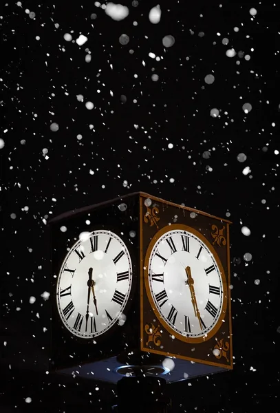 Вуличний годинник увечері, під час снігу — стокове фото