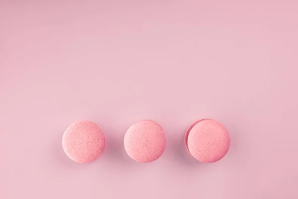 Vista superior de mini macaron rosa sobre un suave fondo de papel rosa dulce. Macaron redondo rosado. dulces populares — Foto de Stock