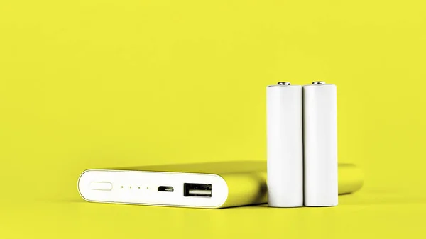 Portable yellow power bank for charging mobile devices and AA batteries. — Stock Photo, Image