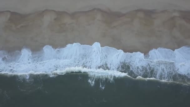 Vliegen over een zandstrand. Golven breken op een zandstrand aan de Atlantische kust, vanuit de lucht. Nazare, Portugal. rauwe video — Stockvideo