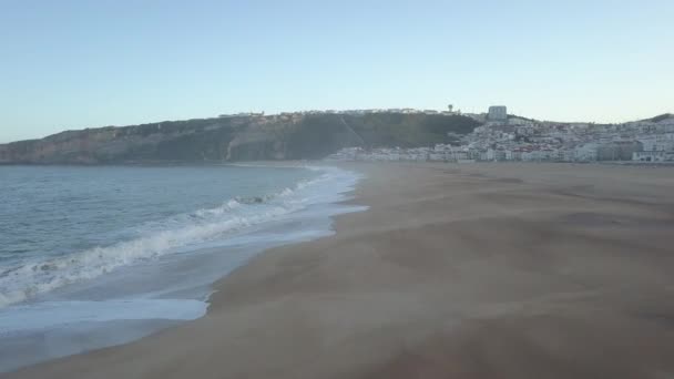 Vliegen over een zandstrand. Golven breken op een zandstrand aan de Atlantische kust, vanuit de lucht. Nazare, Portugal. rauwe video — Stockvideo