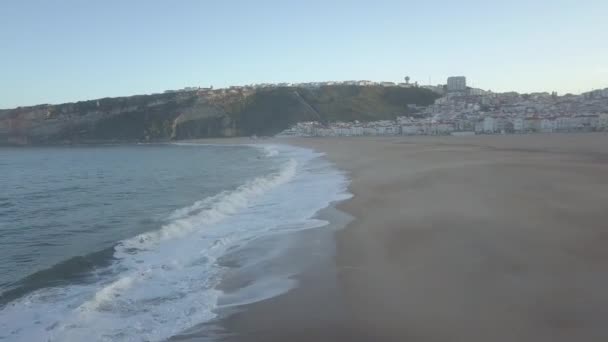 Kumlu bir sahilde uçuyor. Atlantik kıyısında kumlu bir sahilde dalgalar kopuyor, hava manzaralı. Nazare, Portekiz. ham video — Stok video