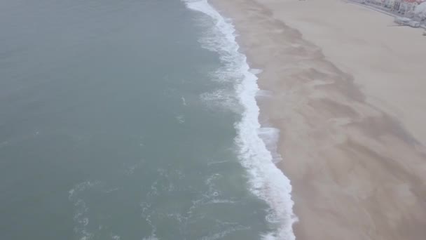 砂浜を飛んでいる 大西洋岸の砂浜 空中ビューで波が壊れます ポルトガルのナザレ 生の映像 — ストック動画