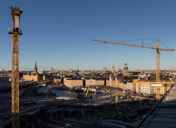 Stockholm şehir merkezinde inşaat alanında. Turnalar, yollar, limanlar, gemiler. Hava güneşli, öğle vakti. Havadan, yukarıdan. Renkli şehir manzarası.