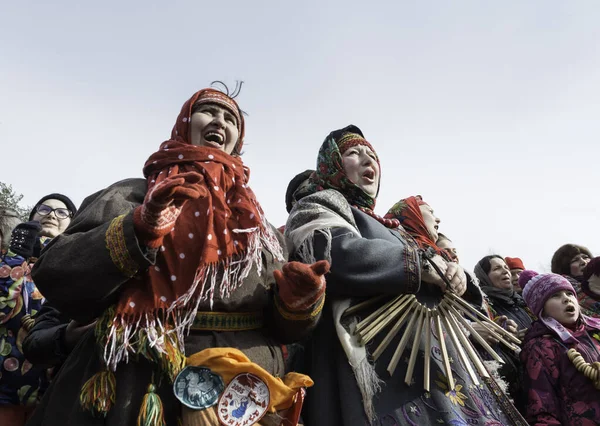 Odintsovo ilçesi, Moskova bölgesi / Rusya - Mar 12020: Geleneksel Rus eşarp ve kostümleri giyen kadınlar şarkı söylüyor ve treshchotka çalıyorlar (diğer adıyla alkışlar). Maslenitsa kutlaması