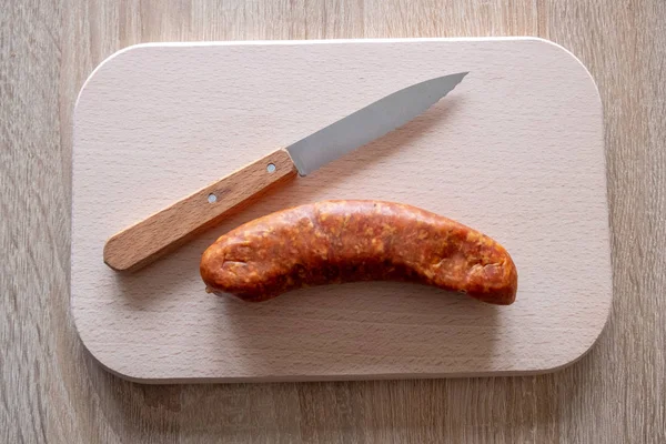 Un knackwurst o salchicha en un plato con un cuchillo para cortar — Foto de Stock