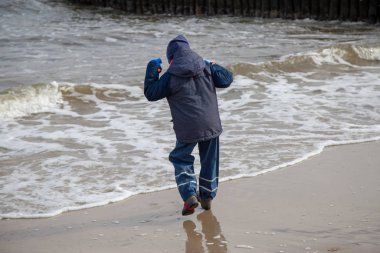 Küçük bir çocuk Kullanım Adası 'ndaki Zempin sahilinde koşar ve dalgalarla oynamaktan mutludur.