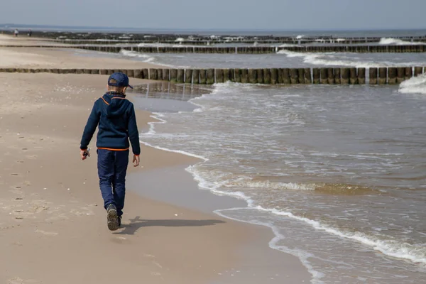 Un petit garçon marche seul le long de la plage et regarde le jeu de — Photo
