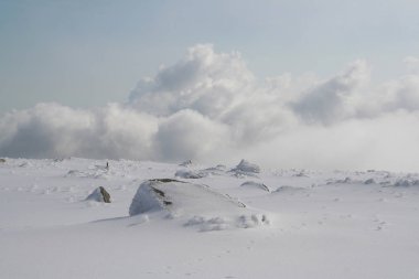 Harz dağlarındaki Brocken manzarası. Bulutlar, kar, mavi gökyüzü ve sis.