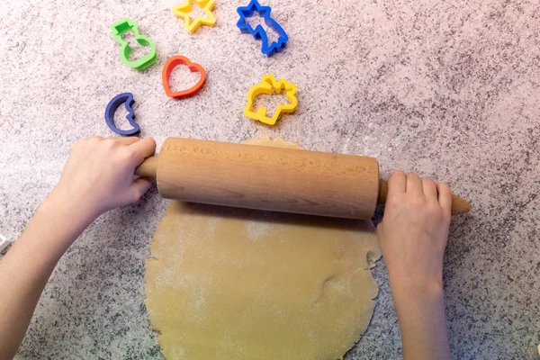 A child bakes cookies with mum or grandma, rolls out the dough and uses moulds to make the cookie cuttings in the Christmas time
