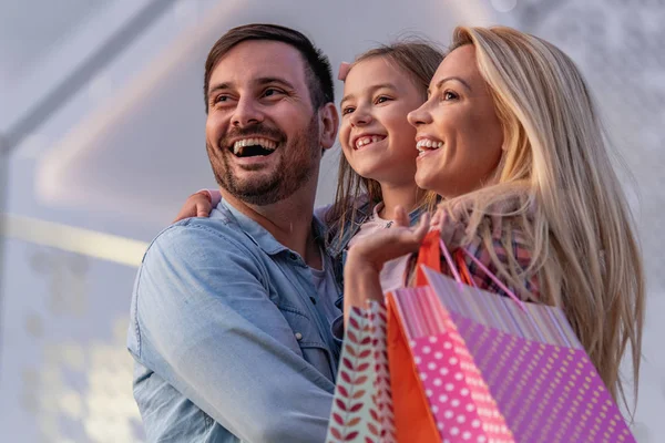 Küçük kızı alışveriş yaptıktan sonra eğlenen neşeli bir aile. İnsanlar, mutluluk, aşk ve tüketim kavramı..