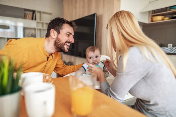 Parents feeding baby son at home