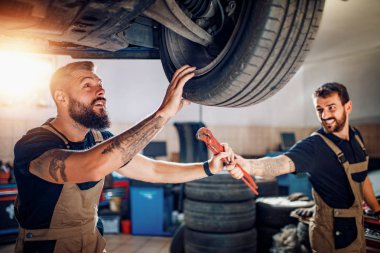 Servis merkezinde araba tamir eden iki tamirci.