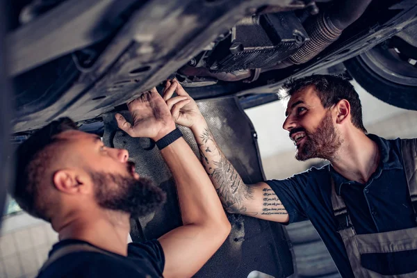Two mechanics repairing car in service center — 스톡 사진
