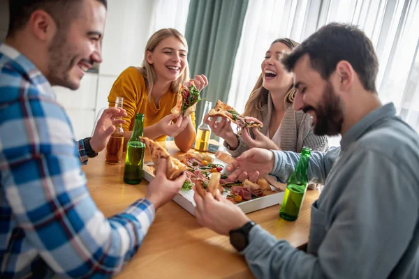 Group of friends eating pizza at home