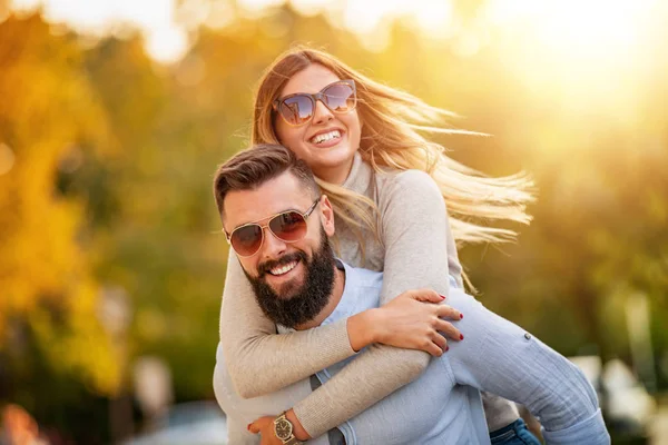 Neşeli, güler yüzlü bir çift dışarıda birbirine sarılıyor.