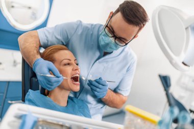 Dişçi ve hasta muayenehanesinde.