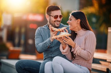 Pizza yiyen mutlu genç bir çiftin fotoğrafı.