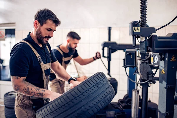 Mechanik pracujący nad oponami samochodowymi w swoim sklepie — Zdjęcie stockowe