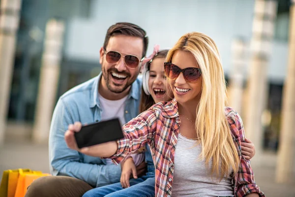 Glückliche junge dreiköpfige Familie lächelt, während sie Zeit miteinander verbringt — Stockfoto