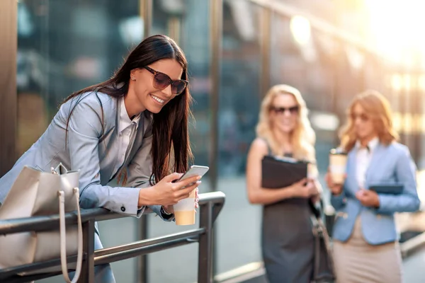 Attractive smiling woman holding phone outdoors