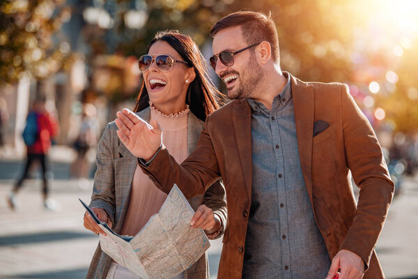 Happy couple  of tourists looking for destination with city map