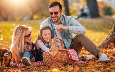 Mutlu aile yaz parkında dinleniyor. Neşeli aile parkta piknik yapıyor. Yaz zamanı ve tatil konsepti..