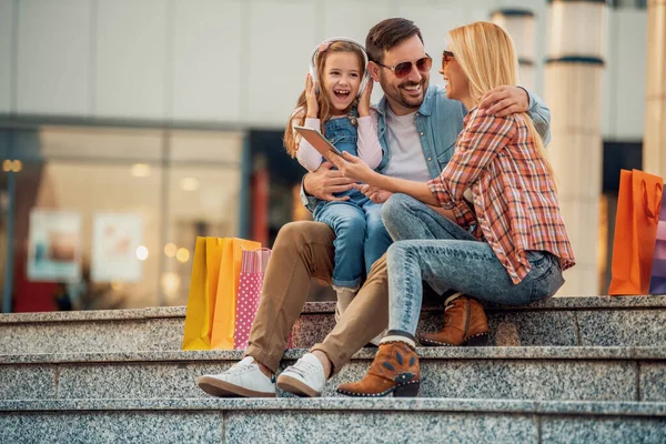 Happy family with shopping bags.Family shopping.Young parents and their daughter are carrying shopping bags.Happy family with shopping bags resting after shopping.