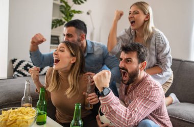 Bir grup arkadaş birlikte maç izliyor. Çok heyecanlı arkadaşlar evde eğleniyor, futbol maçı izliyorlar. Arkadaşlık, kiralama, insanlar ve ev partisi konsepti..