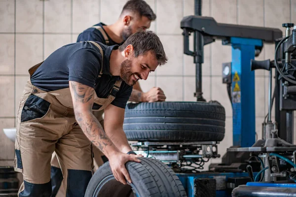 Praca Zespołowa Mechanik Trzymający Oponę Warsztacie Wymiana Opon Zimowych Letnich — Zdjęcie stockowe