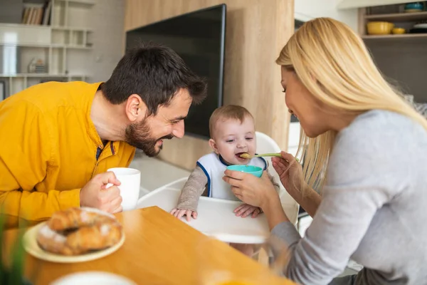 Parents feeding baby together.Father and mother feeding their cute baby boy.