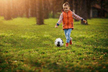 Çocuk kaleye ateş ediyor. Küçük çocuk futbol sahasında futbol oynuyor.
