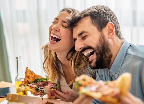 Cheerful couple eating delicious pizza.Happy couple having party at home.People,happiness and fun concept.