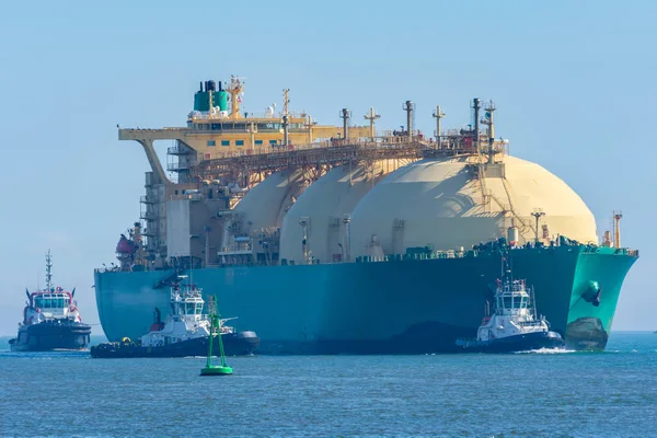 Römorkörlerle birlikte limana giren bir gemi.