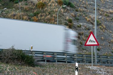 Şiddetli rüzgarların tehlikesinin trafik uyarısı. Otobandan geçen ve hareket eden bir kamyon var..