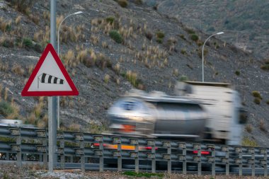 Şiddetli rüzgarların tehlikesinin trafik uyarısı. Otobandan geçen ve hareket eden bir kamyon var..