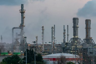 Rafineri manzarası, rafine kuleleri ve tüten bacaları var.