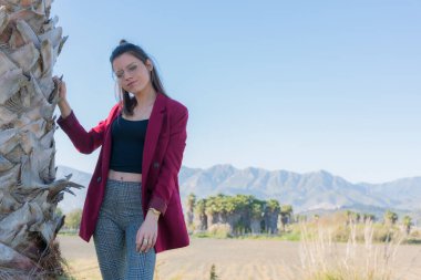 Genç ve dost canlısı bir kadın, bir palmiye ağacının yanında poz veriyor.